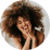 Woman with curly hair smiling cheerfully, hands on cheeks.