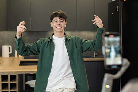 Person in a green shirt gesturing with both hands in a kitchen.